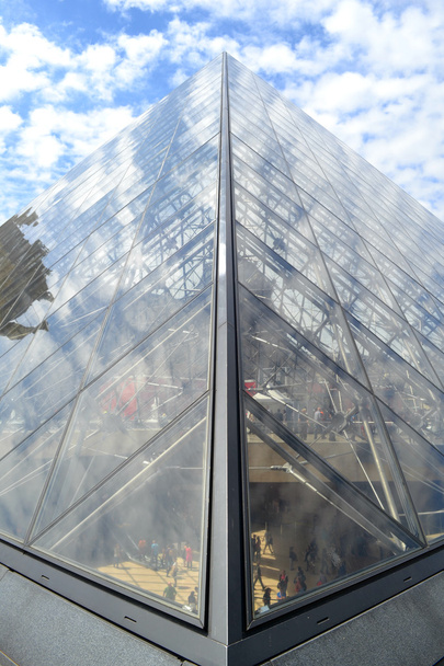 PARIS, FRANCE - 25 MAY, 2015: Famous Louvre Museum Pyramid made of glass with reflections of blue sky and clouds - Foto, afbeelding
