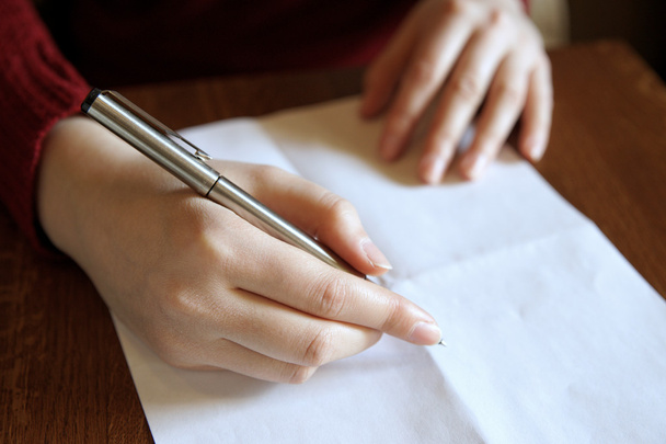 Mano humana con un bolígrafo y una hoja de papel en blanco
. - Foto, Imagen