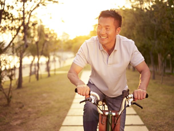 アジア男夕日屋外で自転車に乗る - 写真・画像