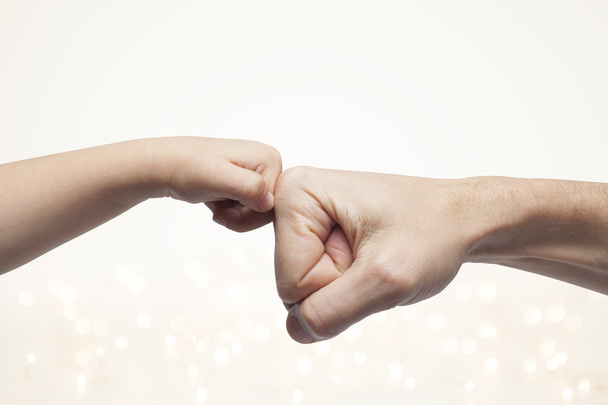 father and son punching fists for agreement on christmas lights background. - Photo, Image