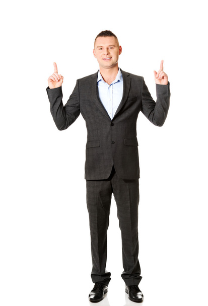 Young businessman pointing upwards  - 写真・画像