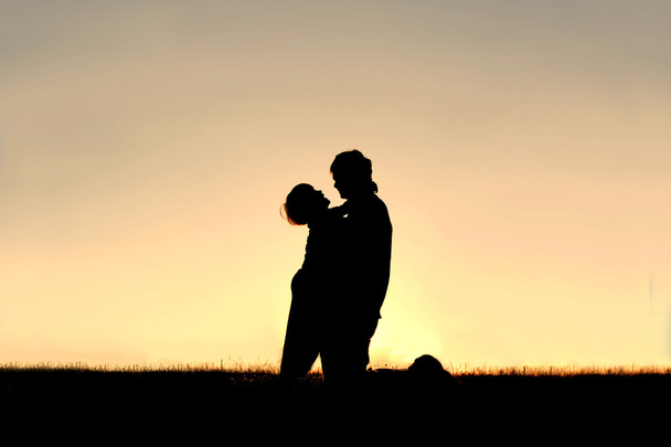 Siluetti lapsi nauraa ja halaus isä auringonlaskun aikaan
 - Valokuva, kuva