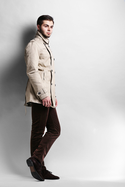 junger Mann im Mantel auf grauem Hintergrund - Foto, Bild