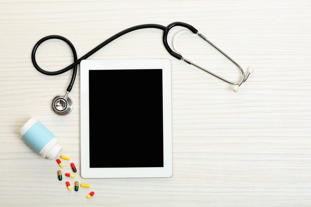 Medical tablet with stethoscope on wooden background - Φωτογραφία, εικόνα