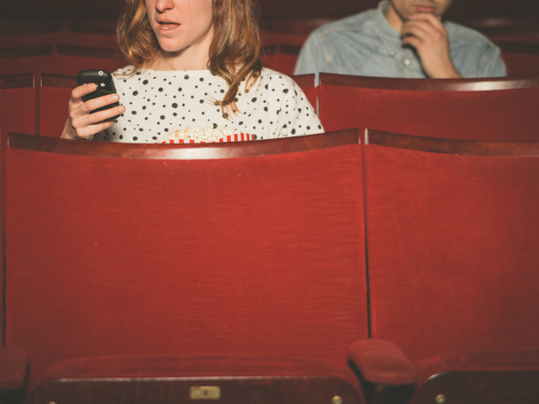 Woman using her phone in theater - Fotó, kép