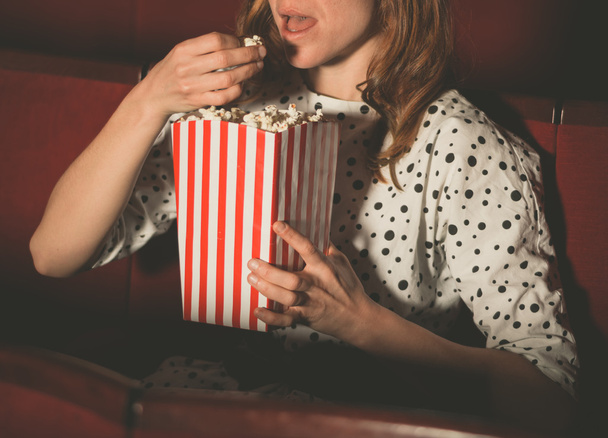 Vrouw eten popcorn en kijken naar film - Foto, afbeelding