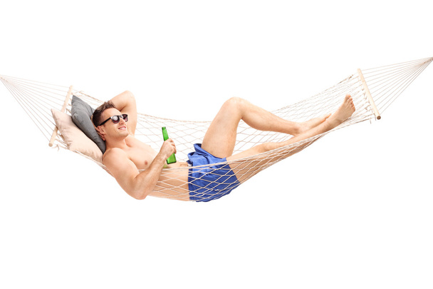Handsome man lying in a hammock with a beer - Zdjęcie, obraz