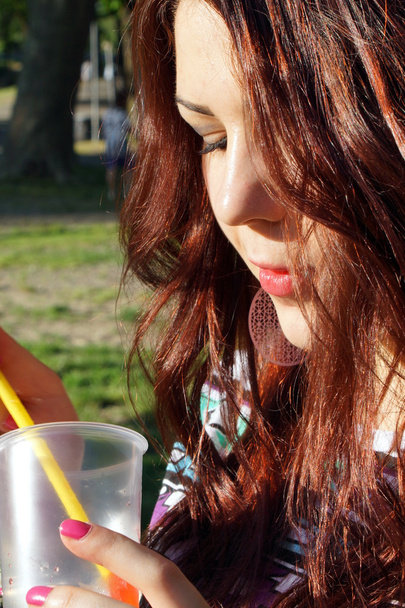 Nuori nainen syö slush puistossa
 - Valokuva, kuva