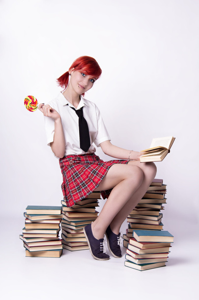 Bir yığın kitap üzerinde oturan lolipop kızla - Fotoğraf, Görsel