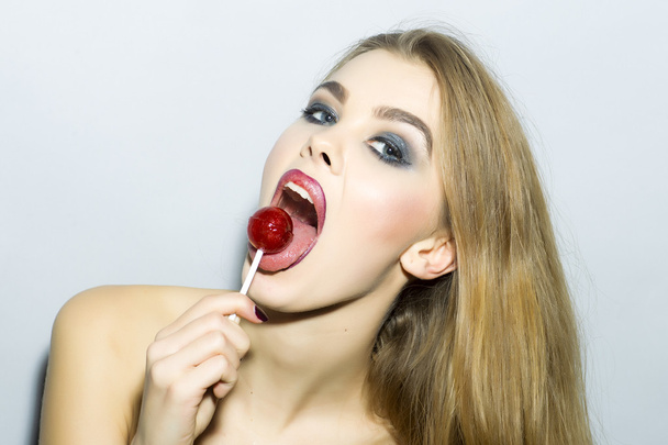 Playful young blonde girl portrait with sugar candy  - Foto, immagini