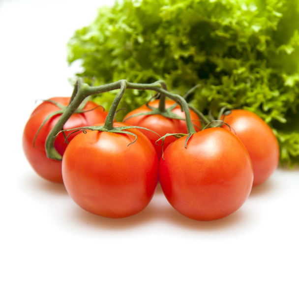 Branch of red ripe tomatoes and bunch of salad - Foto, afbeelding