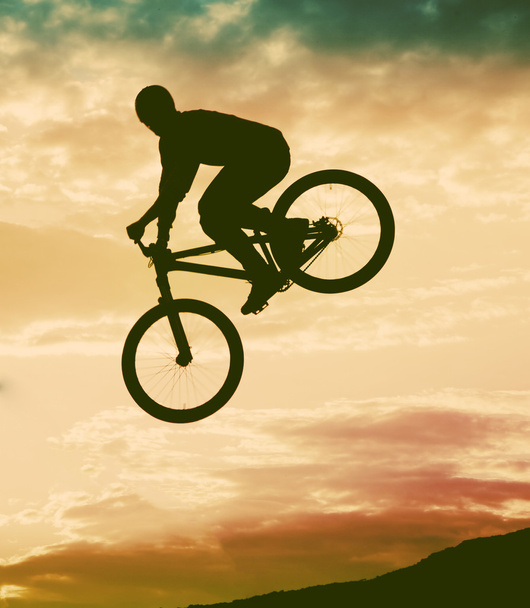 Silhouette d'un homme faisant un saut avec un vélo bmx contre le coucher du soleil
  - Photo, image