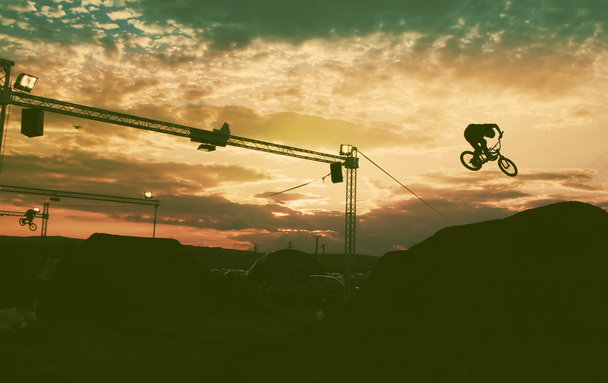Silhouet van een man doen een sprong met een bmx fiets tegen zonsondergang  - Foto, afbeelding