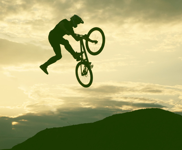 夕日に対して bmx の自転車のジャンプをしている人のシルエット  - 写真・画像