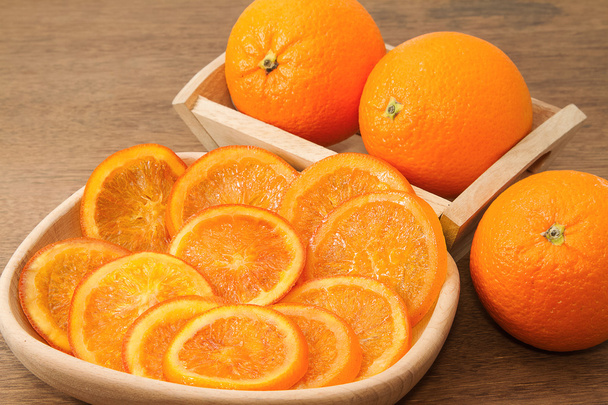 Dried orange slices nad fresh orange on wooden background - Foto, afbeelding