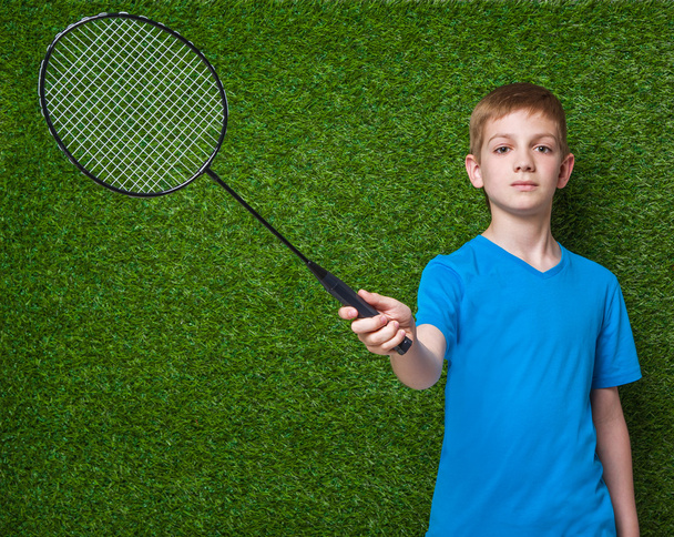 Boy holding badminton racket over green grass - Zdjęcie, obraz