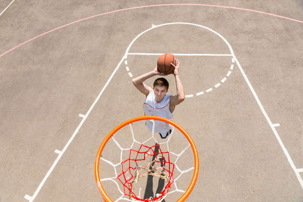 Young Man Making Jump Shot on Basketball Court - Foto, afbeelding