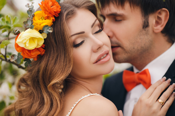 Η νύφη και ο γαμπρός - φωτογραφία σε ένα λουλουδένιο πάρκο την άνοιξη. - Φωτογραφία, εικόνα