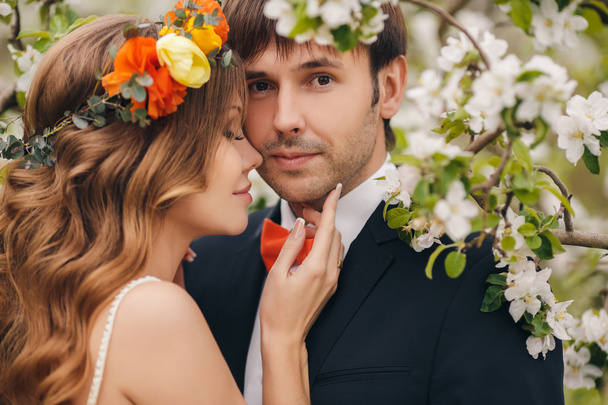 Η νύφη και ο γαμπρός - φωτογραφία σε ένα λουλουδένιο πάρκο την άνοιξη. - Φωτογραφία, εικόνα