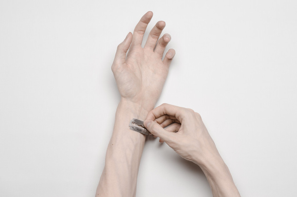 Zelfmoord en Halloween thema: de menselijke hand hebt het mes tot zelfmoord geïsoleerd op een witte achtergrond in studio bovenaanzicht - Foto, afbeelding