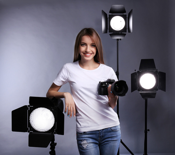 Young female photographer taking photos on grey background - Foto, Imagen