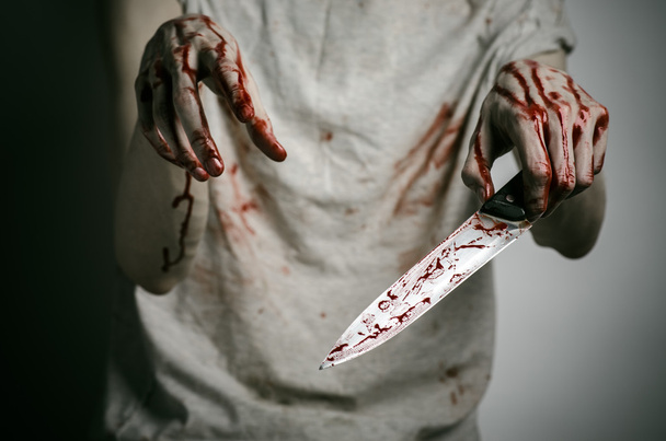 Blood and Halloween theme: man holding a bloody knife in his hand, a bloody murderer - Photo, Image
