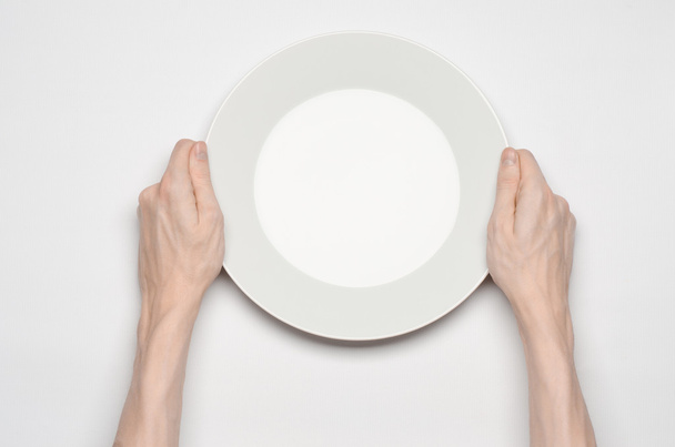 Restaurant and Food theme: the human hand show gesture on an empty white plate on a white background in studio isolated top view - Fotografie, Obrázek