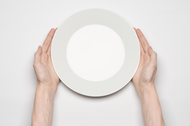 Restaurant and Food theme: the human hand show gesture on an empty white plate on a white background in studio isolated top view - Zdjęcie, obraz