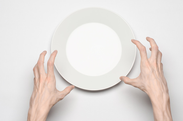 Restaurant and Food theme: the human hand show gesture on an empty white plate on a white background in studio isolated top view - Fotó, kép