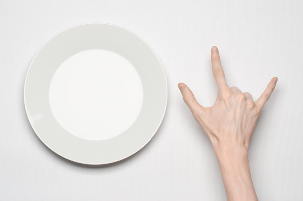 Restaurant and Food theme: the human hand show gesture on an empty white plate on a white background in studio isolated top view - Photo, Image