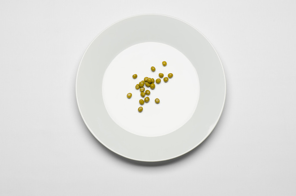 Healthy eating topic: green peas lying on a white plate on a white table in the studio top view - Fotoğraf, Görsel
