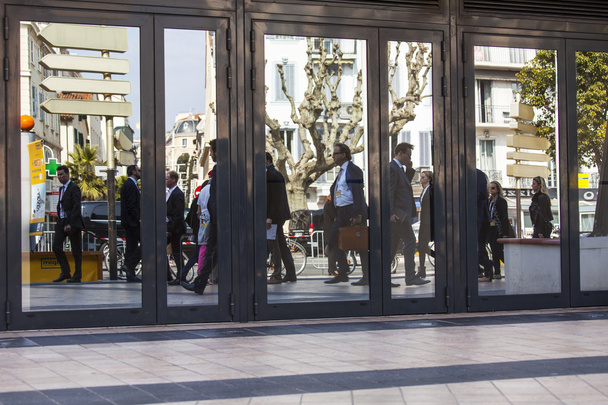 Cannes, Francja, na 12 marca 2015. Typowe miasto krajobraz. Ulicy i przechodniów są odzwierciedlane w drzwi szklane centrum biurowe - Zdjęcie, obraz