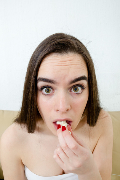 Close up of woman scared funny watching scary movie eating popco - Photo, Image