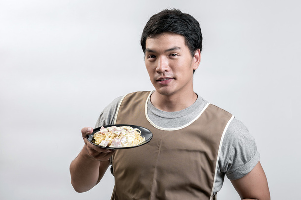 Азіатських людині в фартух з спагетті карбонара - Фото, зображення