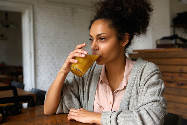 Joven mujer de raza mixta bebiendo jugo de naranja
 - Foto, imagen