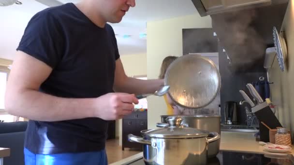 woman with baby in hands and man tasting food in steamy pot. 4K - Footage, Video