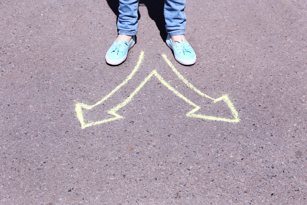 Female feet making choice on asphalt with drawing arrows, outdoors - Fotografie, Obrázek