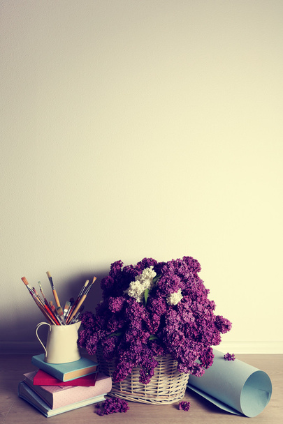 Beautiful lilac flowers on basket on floor in room close-up - Photo, image