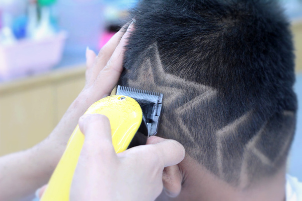 El corte de pelo del niño con el cortador y la navaja de afeitar en la peluquería
 - Foto, imagen