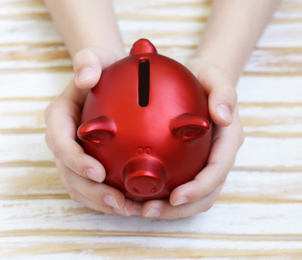 close up of boy's hands holding red piggy bank - Photo, Image