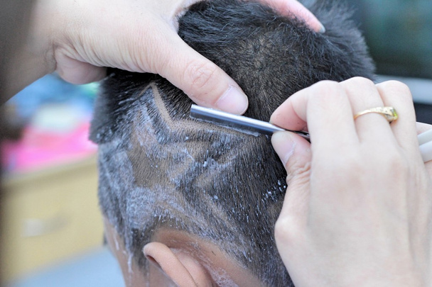 Il taglio di capelli del ragazzo con clipper e rasoio nel negozio di barbiere
 - Foto, immagini