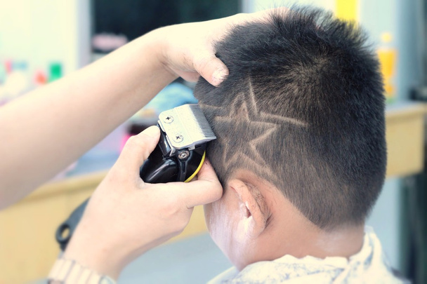 Haarschnitt des Jungen mit Haarschneider und Rasiermesser im Friseurladen - Foto, Bild