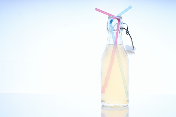 Bottle with cold drink on glass table with two straws - Photo, Image