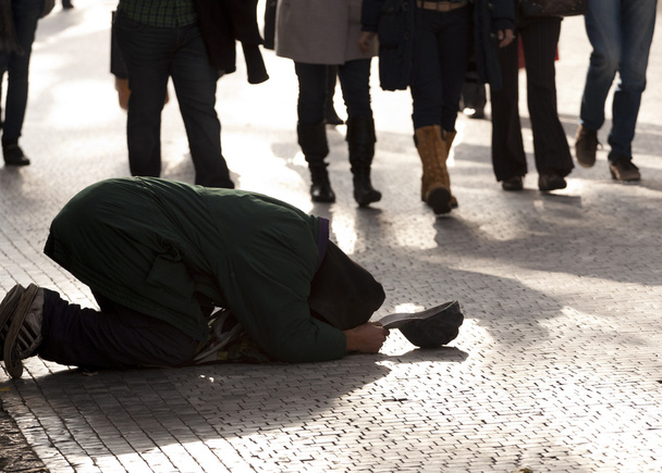 Mendigo arrodillado en un pavimento
 - Foto, Imagen
