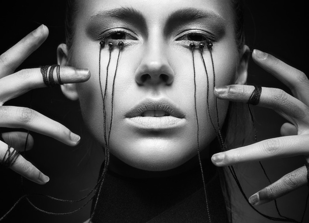 Beautiful girl with creative make-up in Gothic style and the threads of eyes. Black and white photo - Valokuva, kuva