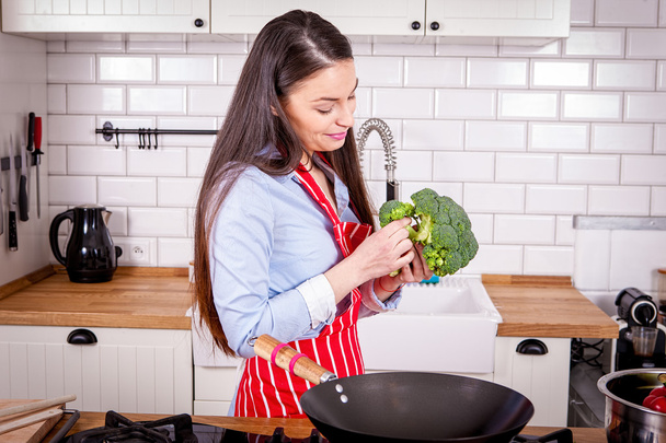 Молодая женщина готовит брокколи на кухне
. - Фото, изображение