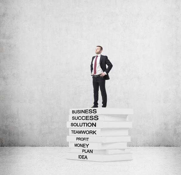 A student in a formal suit is standing on the top of the books' pedestal - Photo, Image