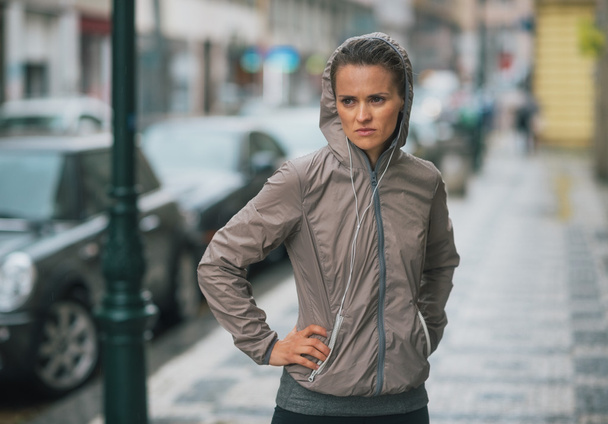 Woman runner wearing rain gear stopped and feeling unmotivated - Foto, Bild