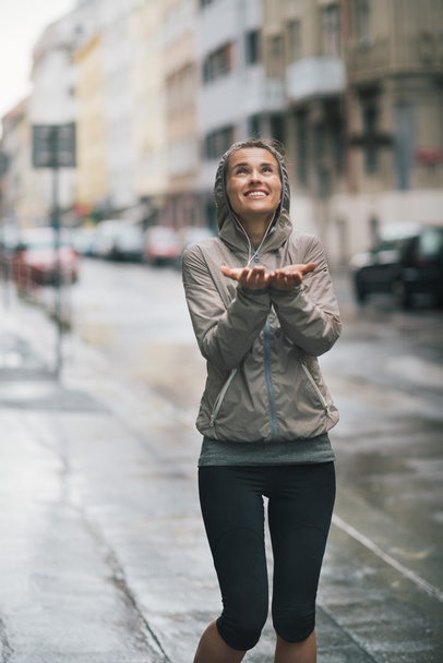 Athletic, happy woman holding her hands out to catch rain drops - Foto, Imagen