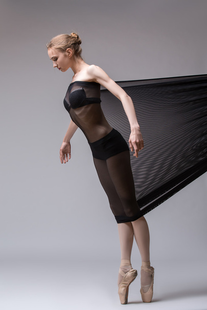 Slim dancer plays with black mesh fabric - Фото, зображення